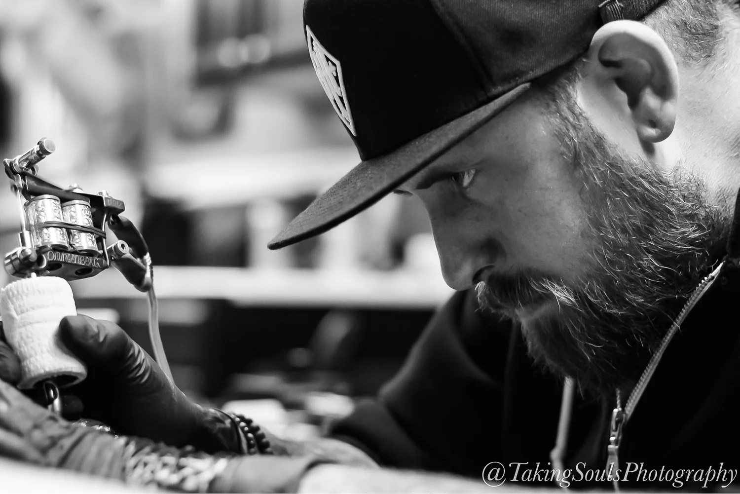 A Heritage artist tattooing, in black and white